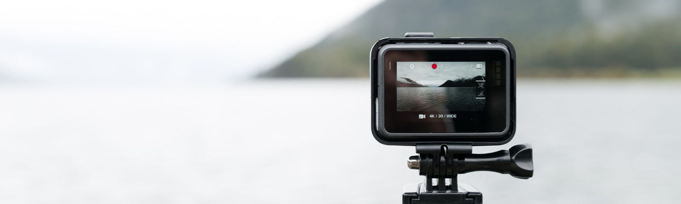 GoPro Kamera auf einem Stativ die eine Aufnahme von Wasser und Bergen macht - GoPro mieten