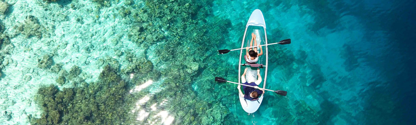 Paar auf einem durchsichtigen Paddel-Boot von oben in Türkisblauem Wasser fotografiert - Wassersportgeräte mieten