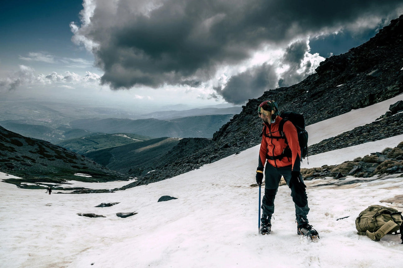 Mann auf verschneiten Berg und schaut nach hinten ins Tal: Winterausrüstung mieten