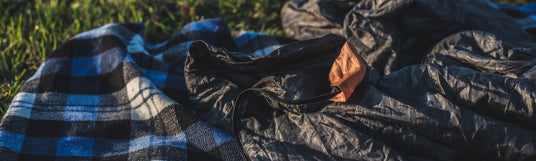 Biwaksack liegt auf einer Decke im Gras