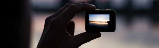 Person hält im dunklen eine GoPro und filmt am See den Sonnenuntergang