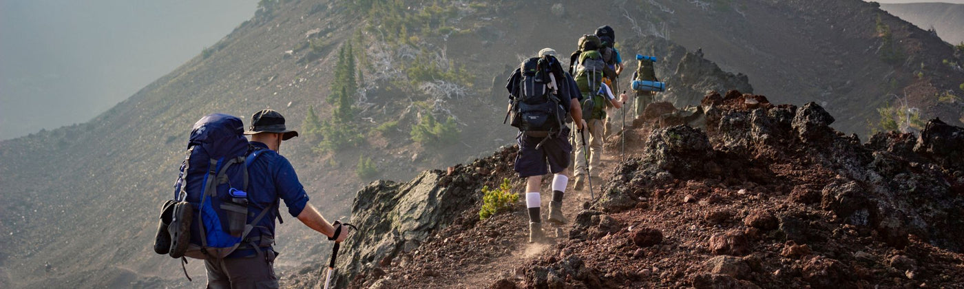 Gruppe die über einen Bergkamm wandert: Rucksack mieten