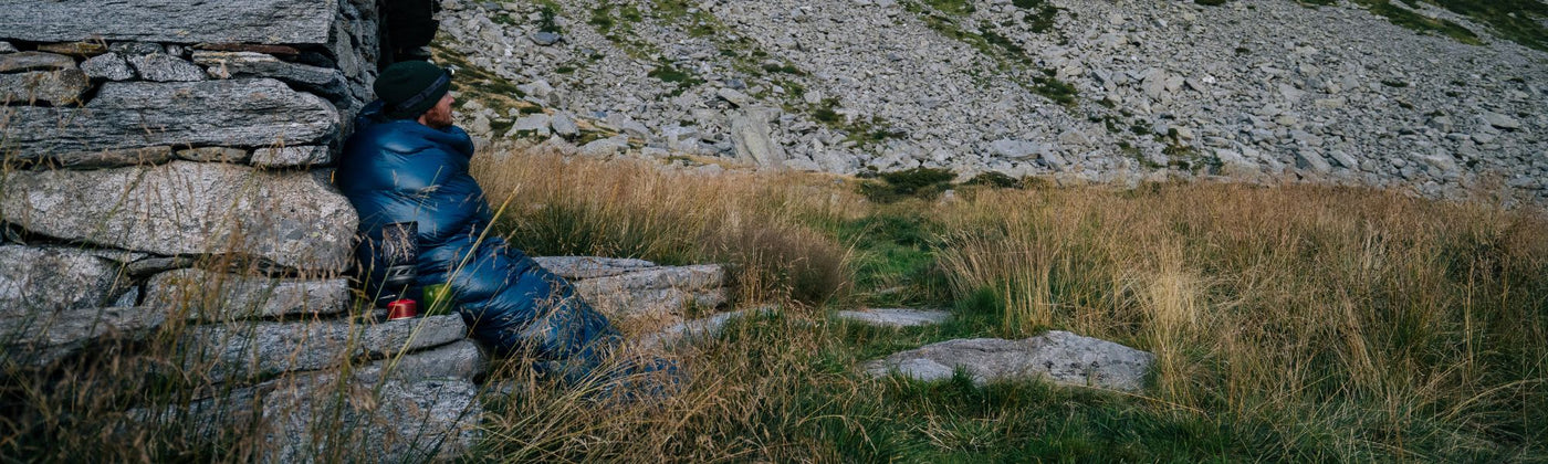 Mann in Schlafsack und schaut in die Natur: Schlafsack mieten