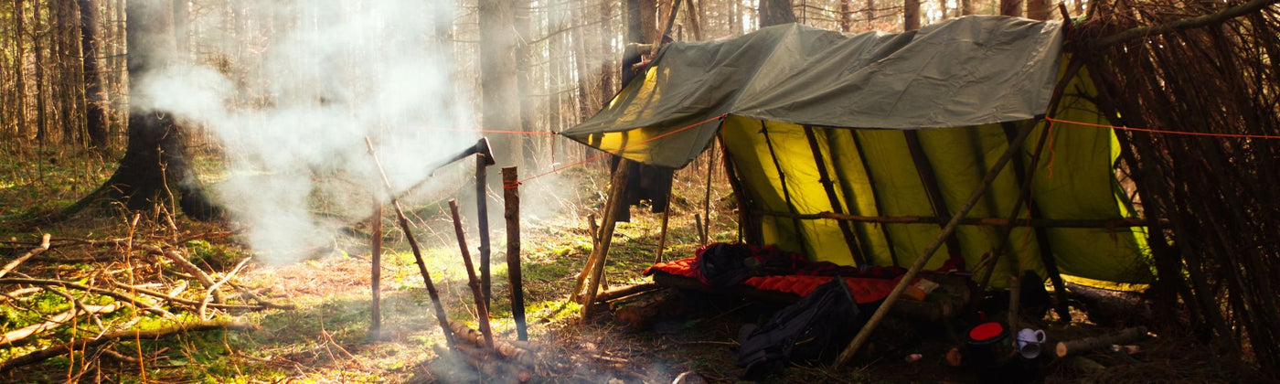 Shelter der mit einem Tarp und Holz gebaut wurde im Wald: Tarp mieten